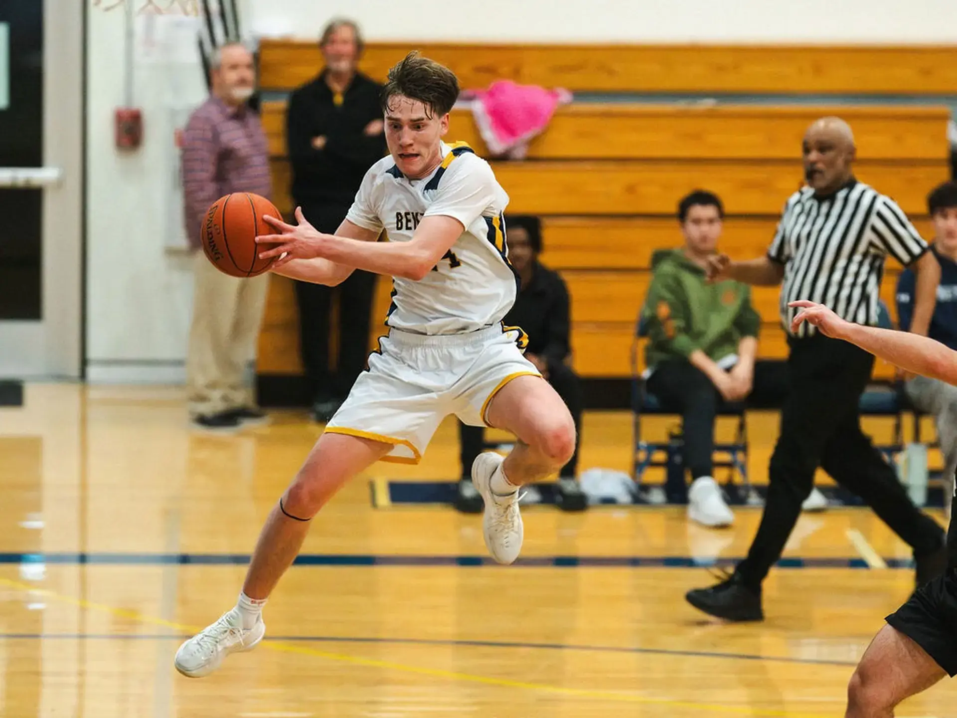 Upper School Boys' Basketball player jumping in air with basketball. 