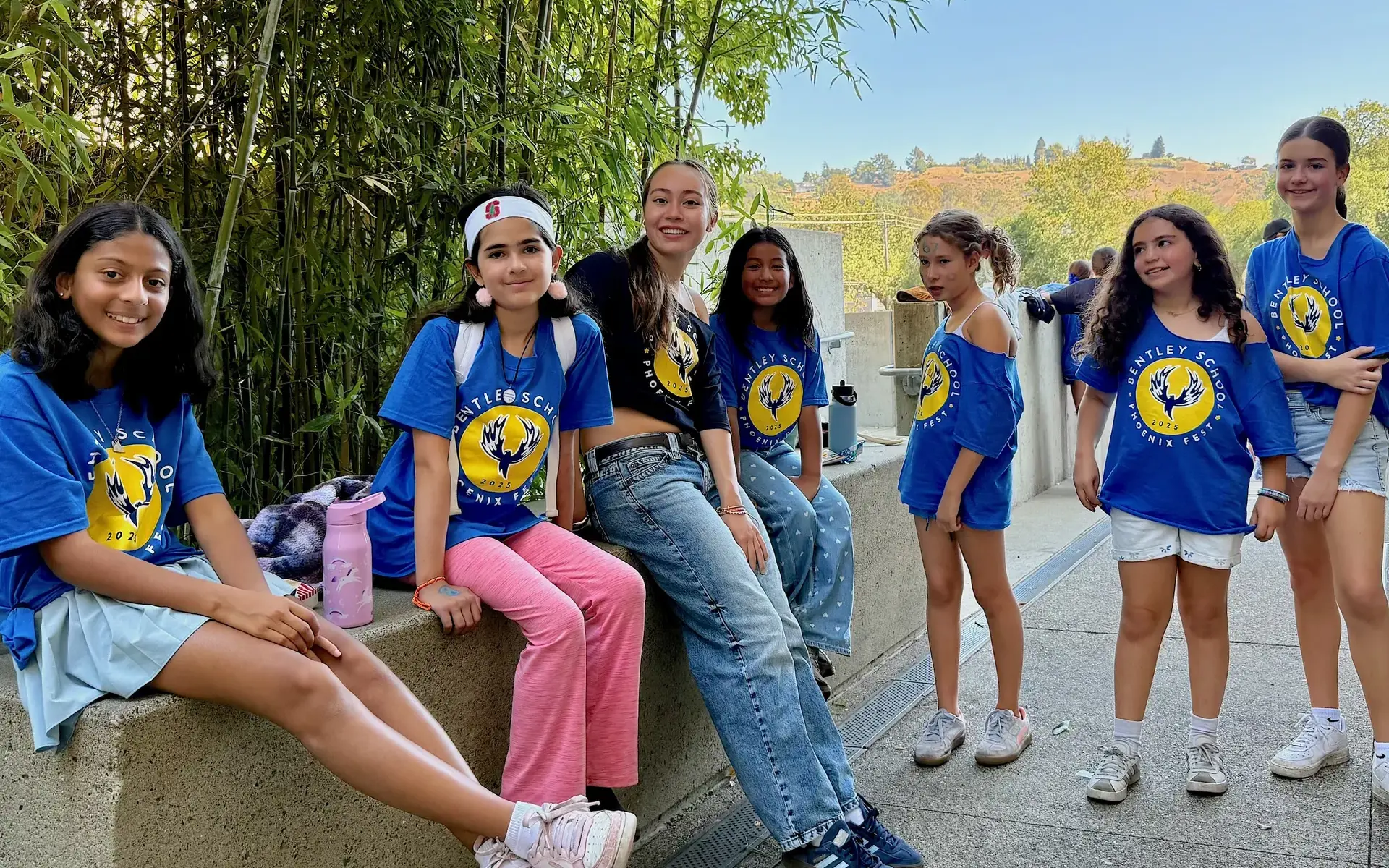 5th grade girls smile with an Upper School girl outside the Athletic Center at Phoenix Fest. 