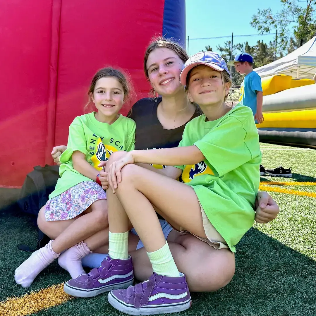 Two Lower School students sit with an Upper School girl at Phoenix Fest.