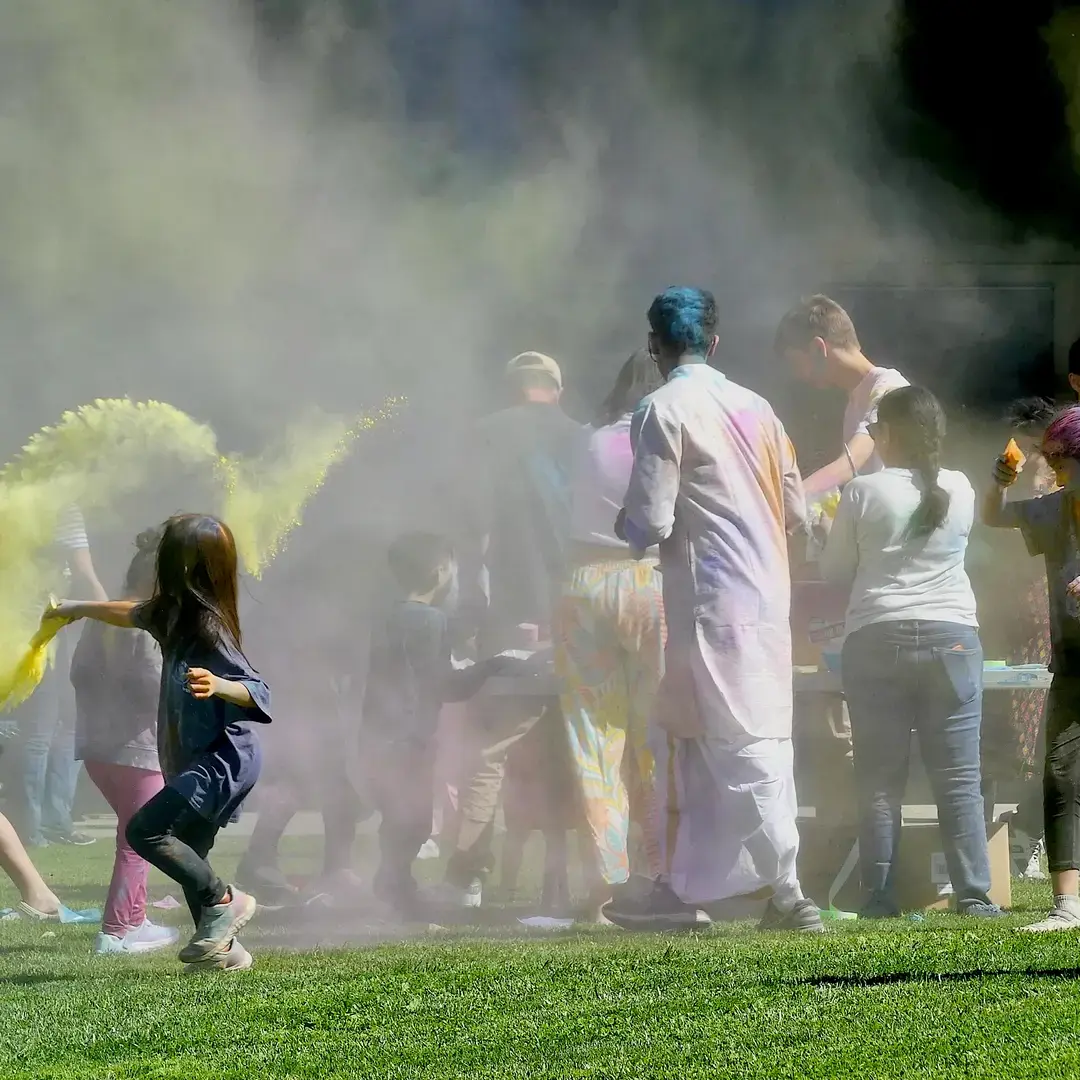 Students of all ages run and throw colored powder to celebrate Holi during Bentley's International Day.