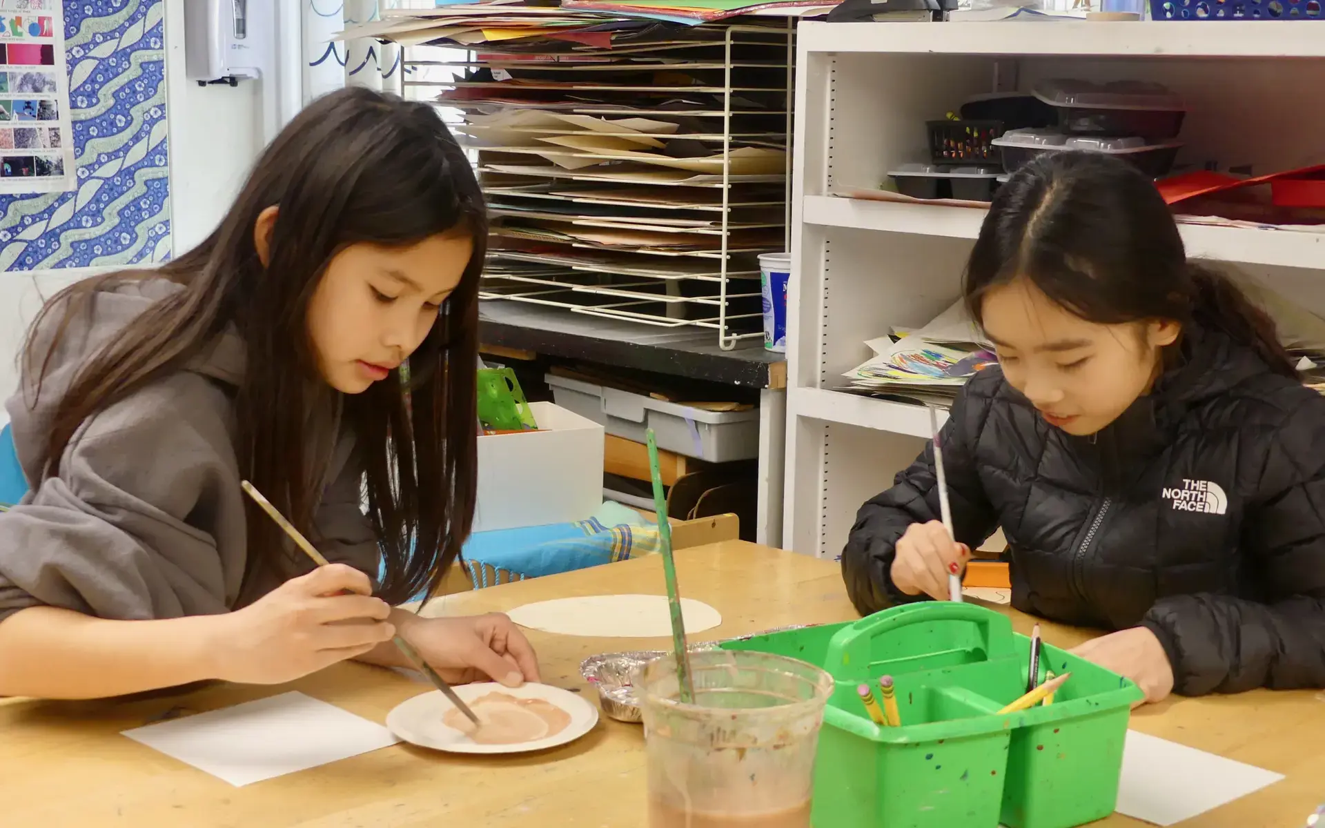 Two Lower School girls work on paintings in the Art Studio.