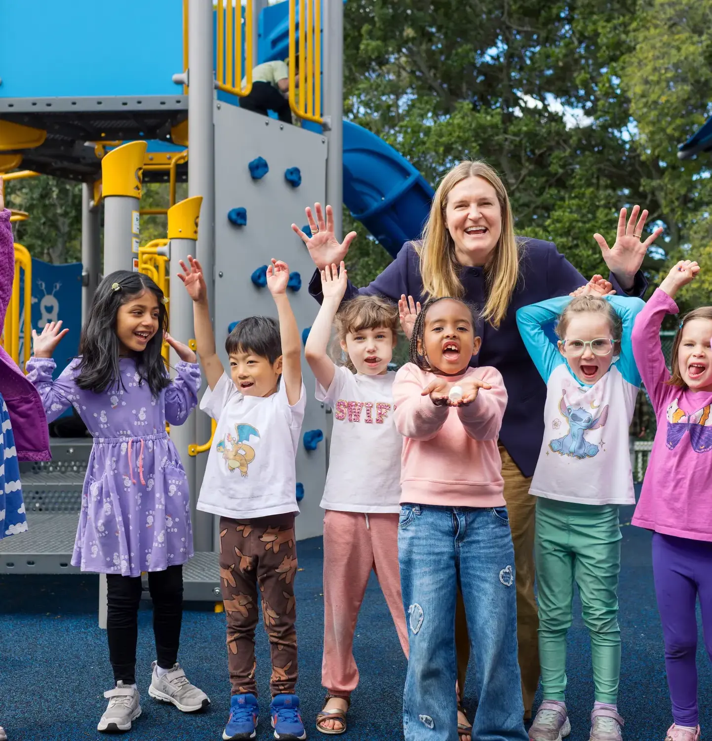 Kindergarten students cheering on the playground with Head of School Christie Moncharmon