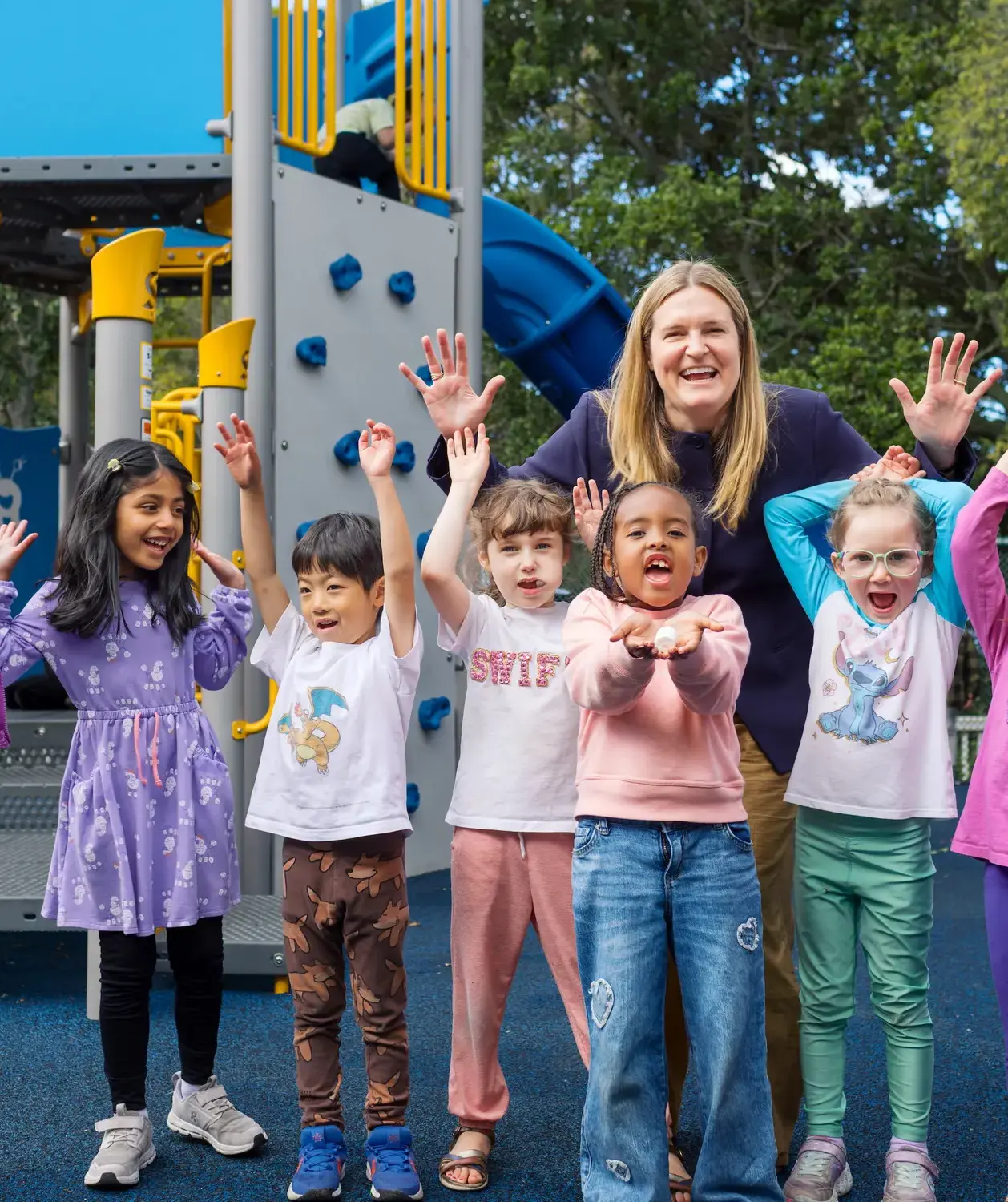 Kindergarten students cheering on the playground with Head of School Christie Moncharmont. 