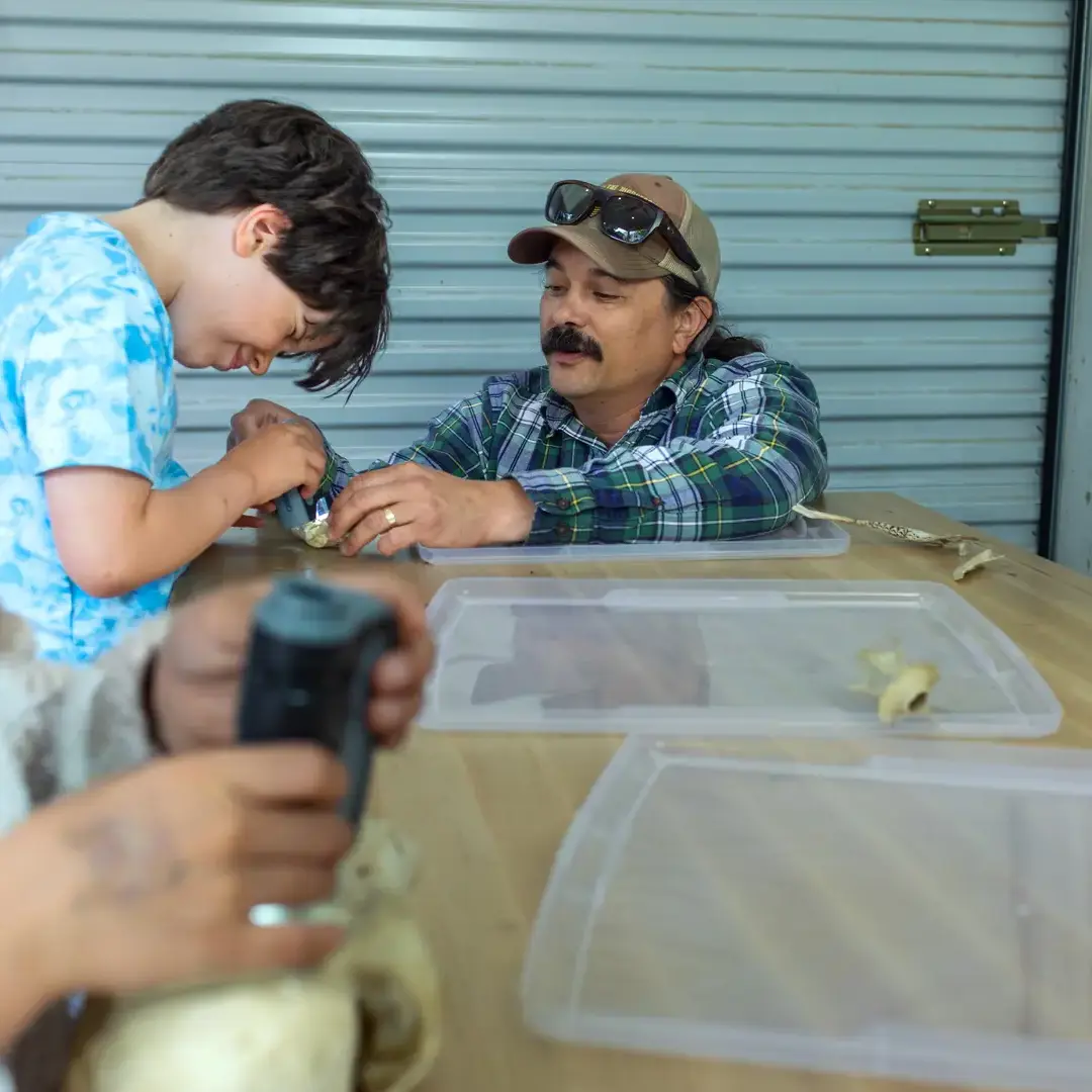 A 1st-grader looks through a microscope with his teacher in the Maker Space. 