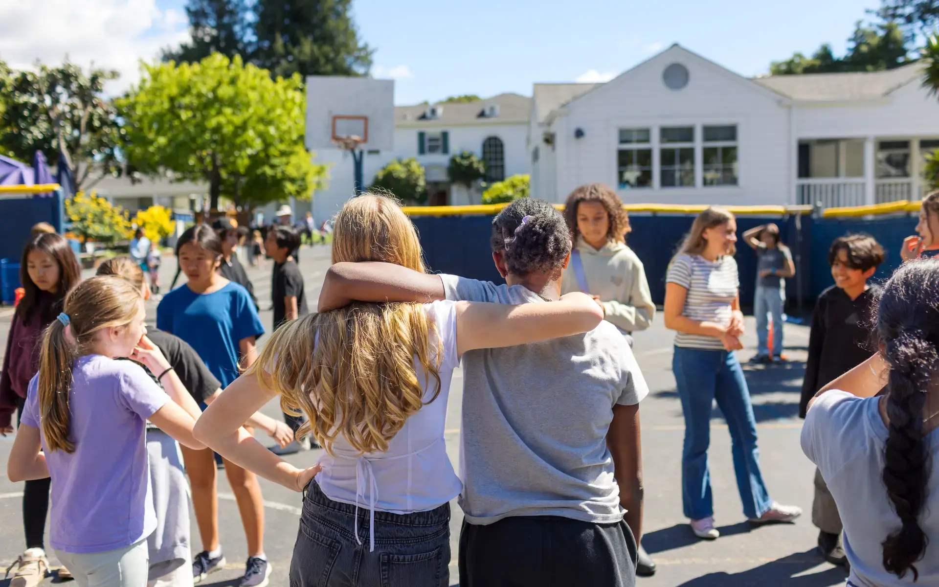 Middle School girls with arms around one another on the basketball courts.