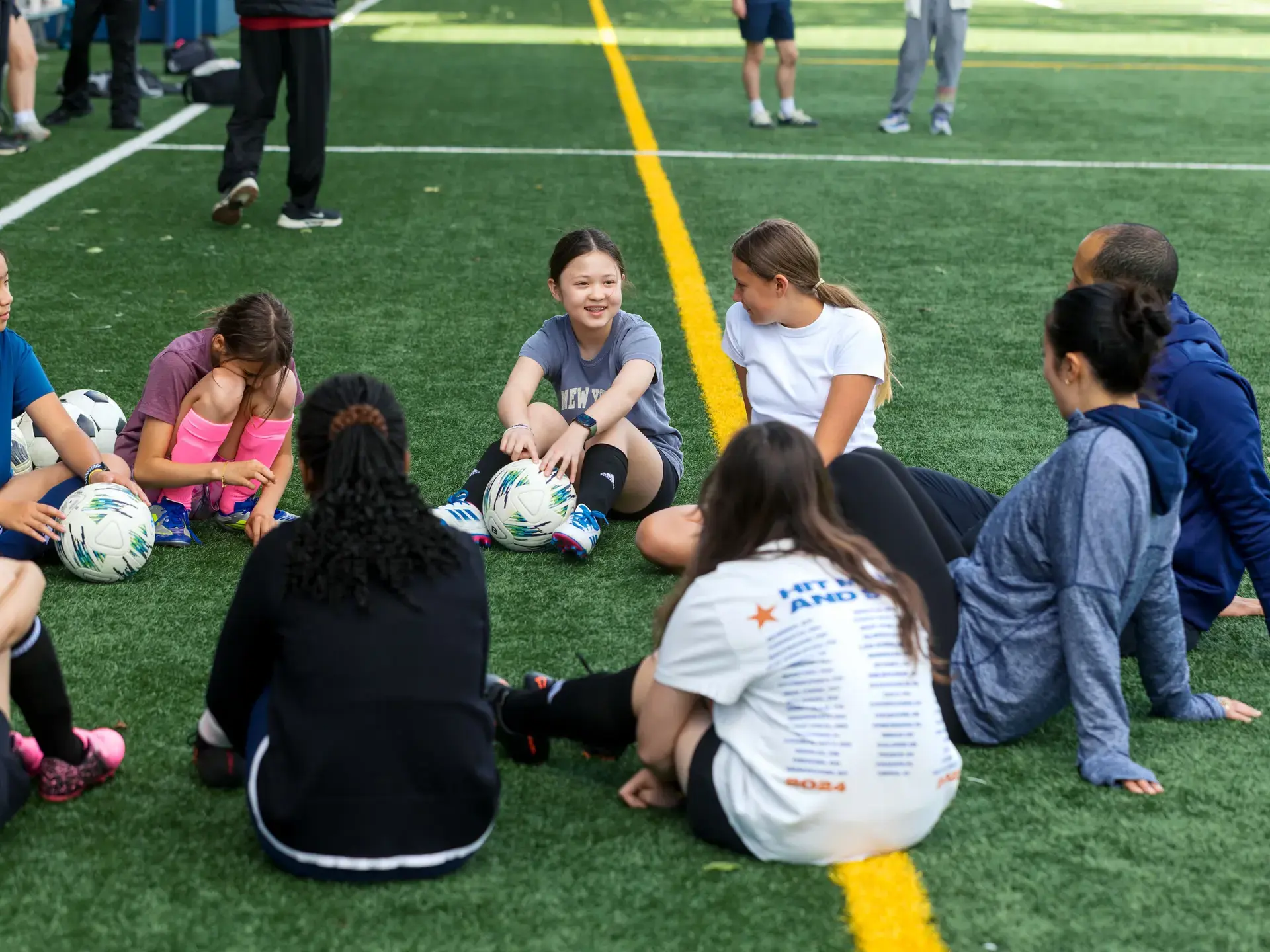 Group of Middle School students sitting on field and talking.