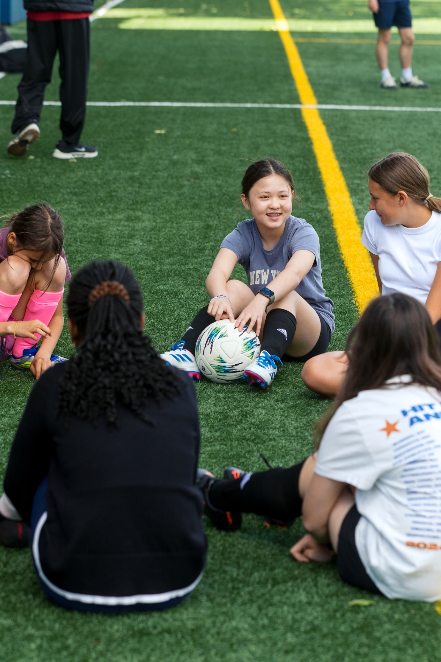 students sitting together on the field during a soccer practice break