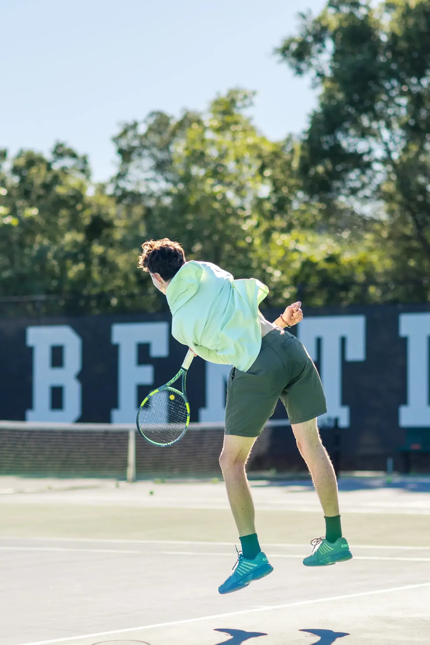 Upper School boy serves tennis ball on Bentley courts.