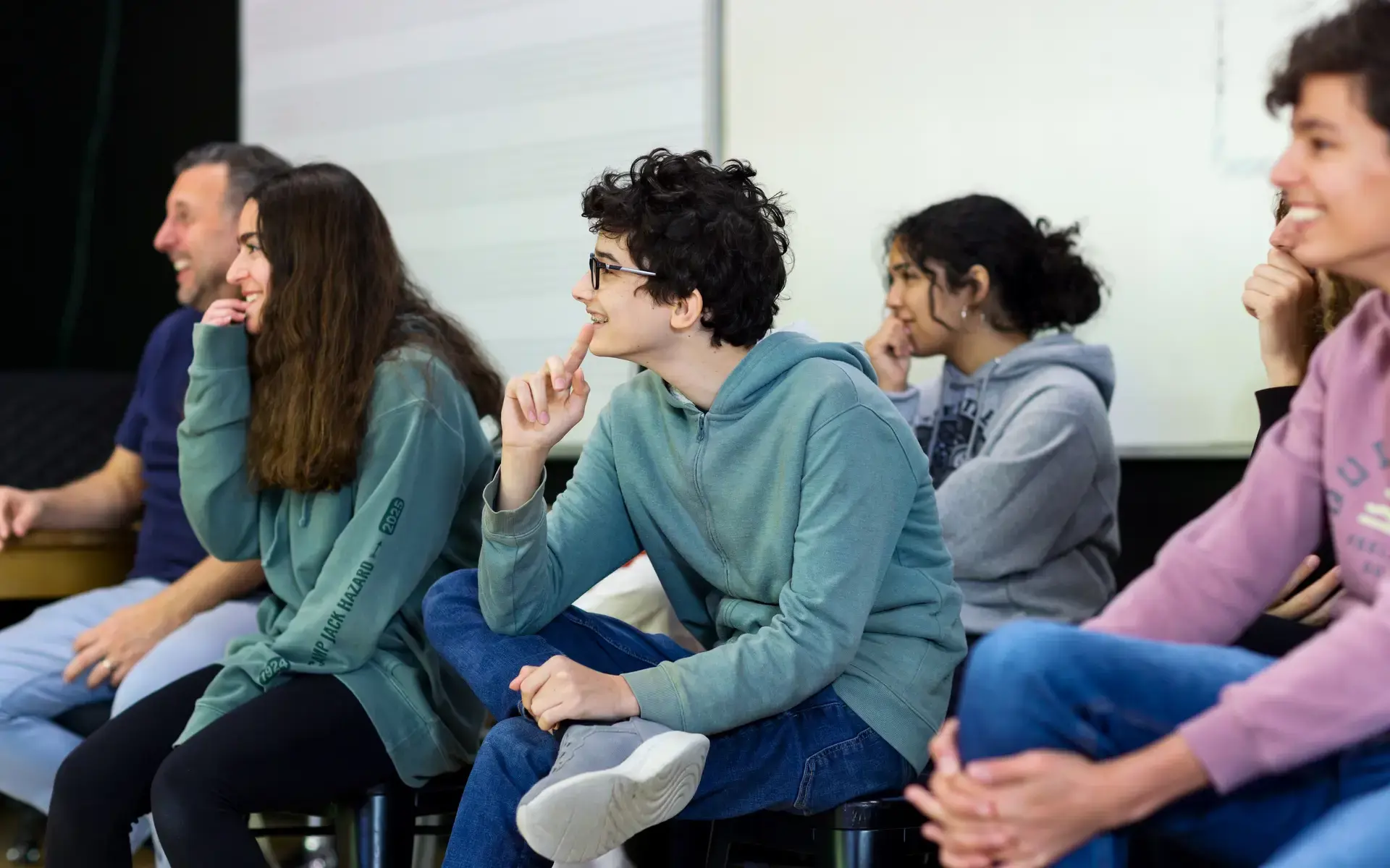A group of Upper School students laugh together while seated in the Little Theater.