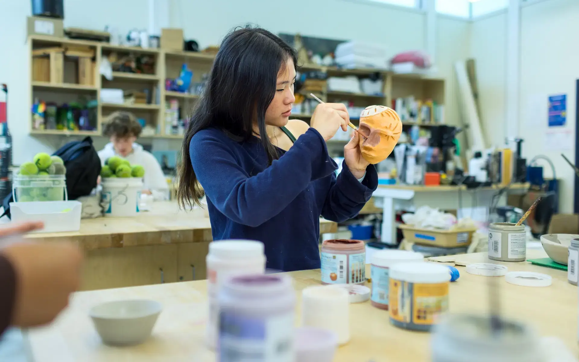 An Upper School girl paints her ceramic mask in the Art Studio.