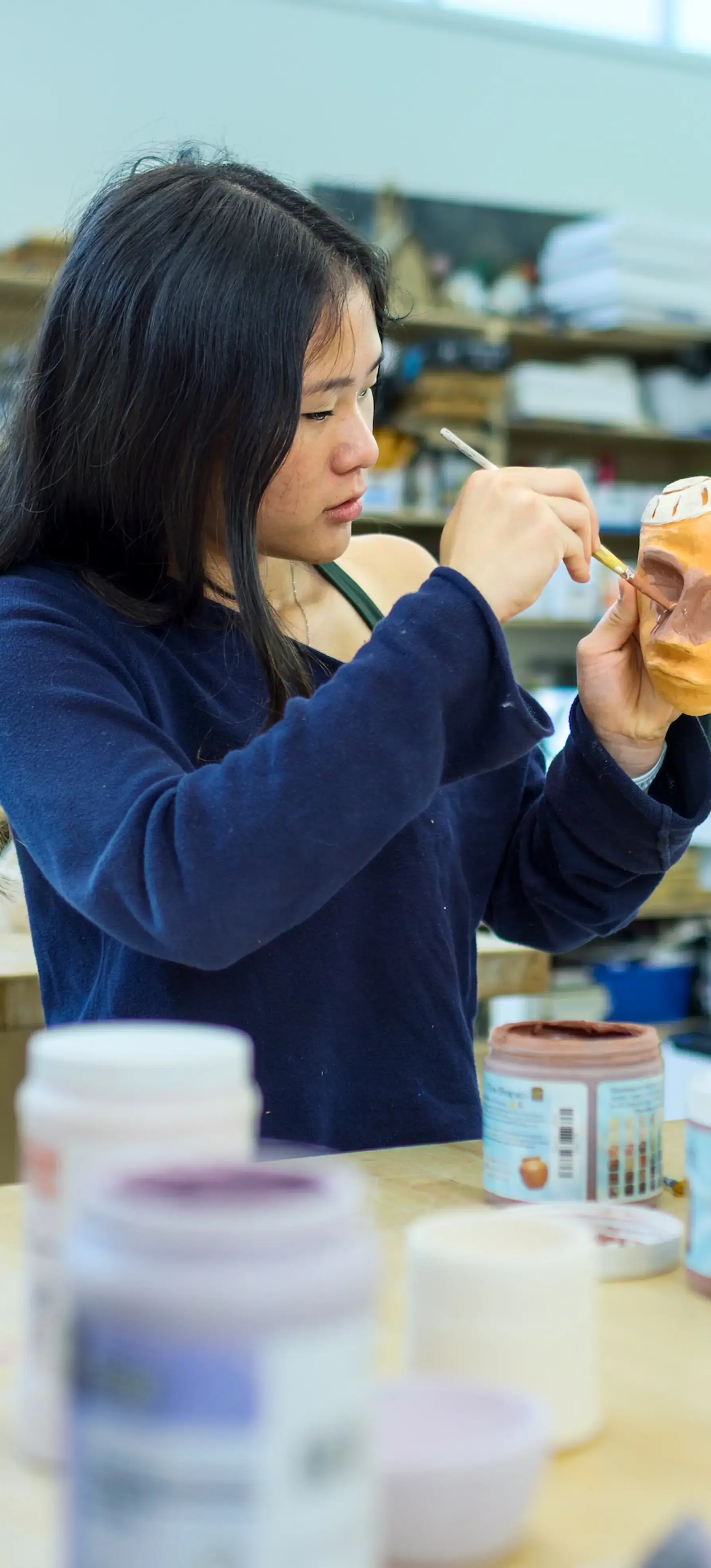 Upper School girl painting ceramics project in the art studio. 